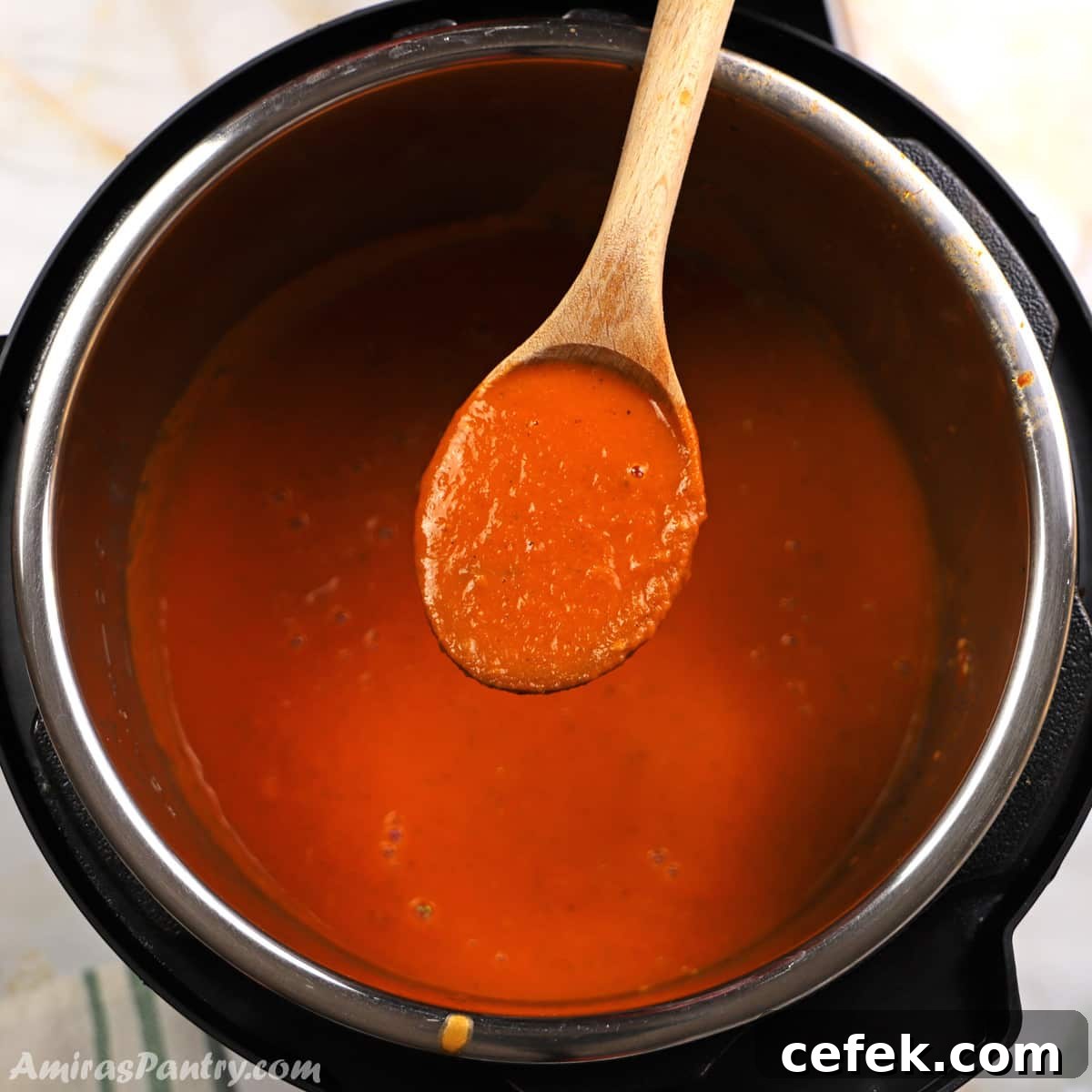 A wooden spoon scooping some tomato soup out of the instant pot.