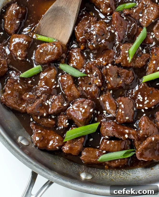 Mongolian Beef and scallions in a skillet with wooden spoon
