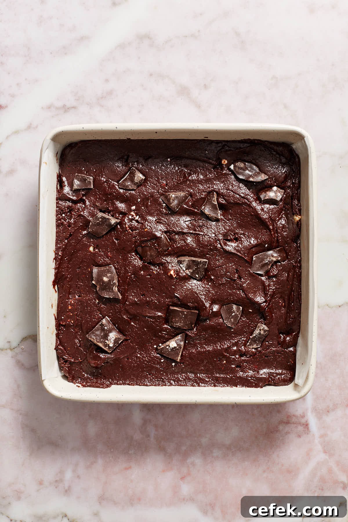 Brownie batter spread out in prepared pan with peppermint bark pressed into the top.