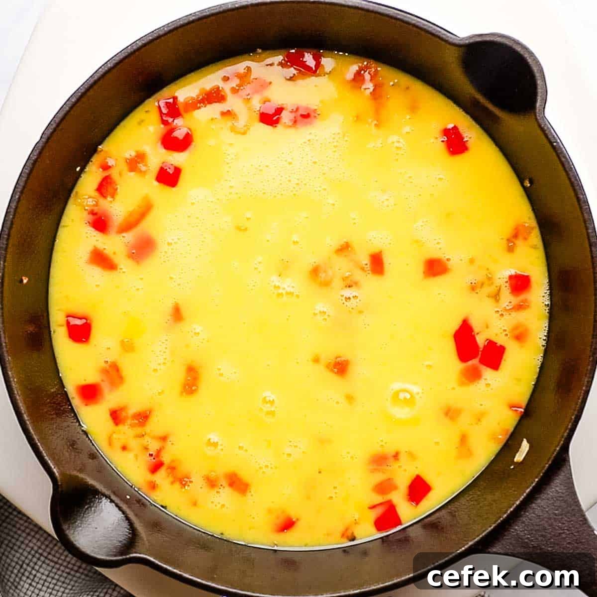egg mixture added to the cast iron skillet on top of the cooked onions and bell pepper