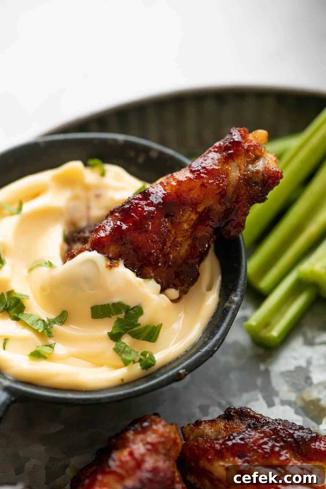 A single chicken wing dipped into aioli