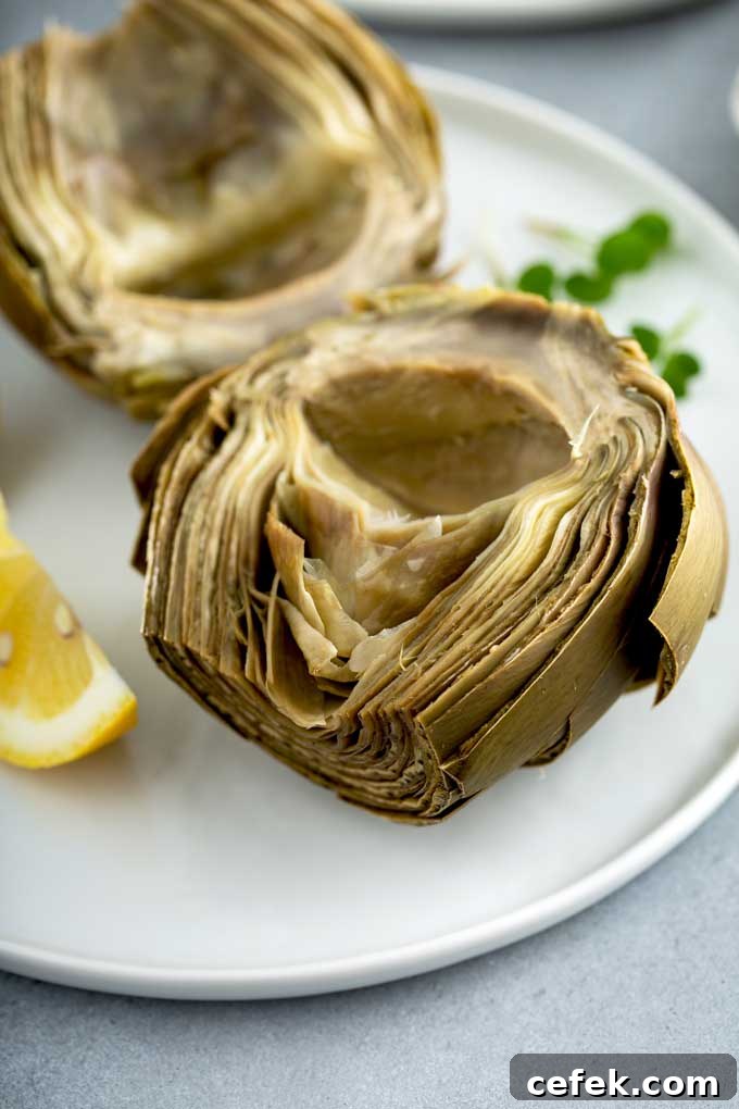 A cooked artichoke cut in half on a white plate.