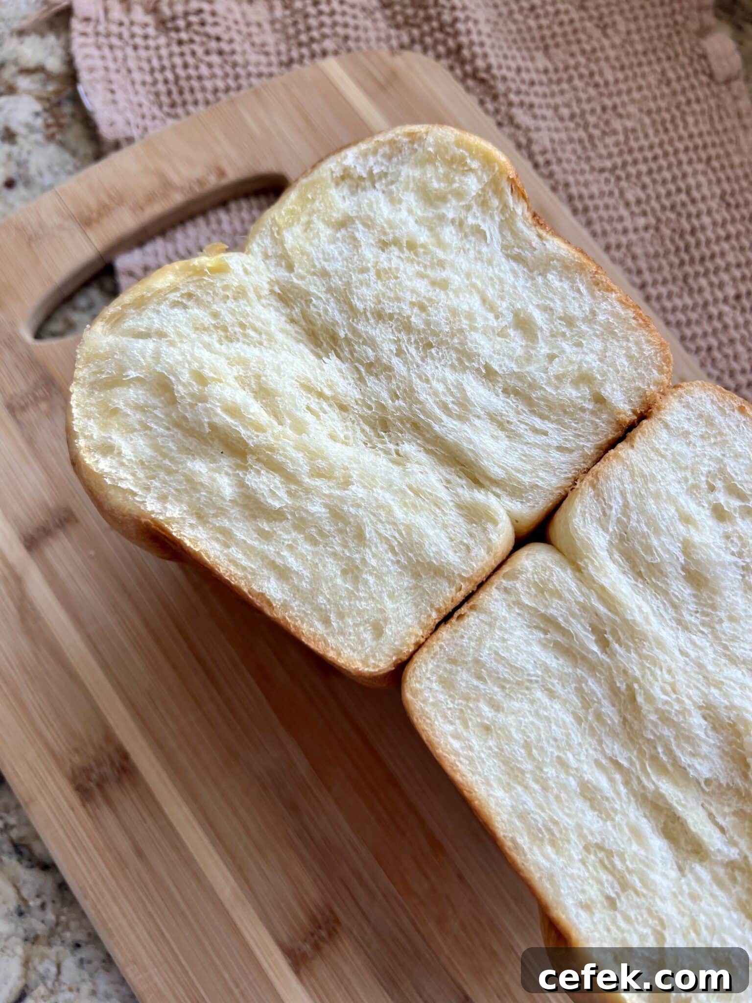 A loaf of sourdough brioche is cut in half, revealing a soft pillowy center.