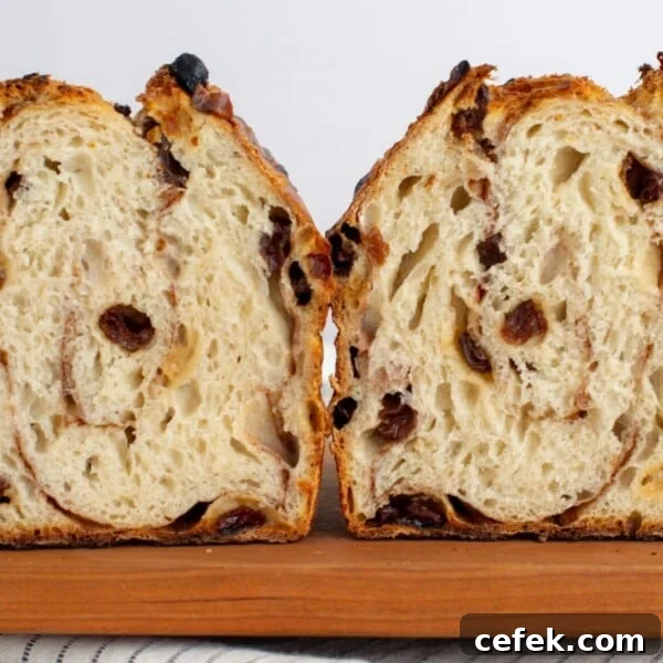 Sourdough cinnamon raisin bagel bread cut in half sitting on a cutting board.