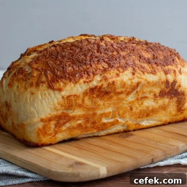 Sourdough Asiago Bagel bread loaf on a cutting board.