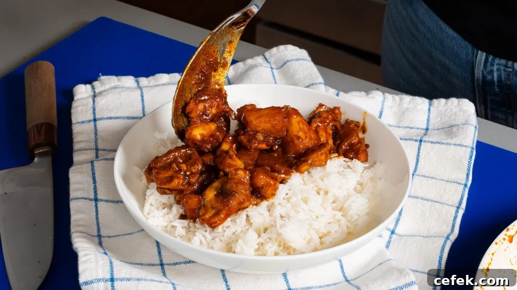 Spooning glossy chipotle chicken over rice.