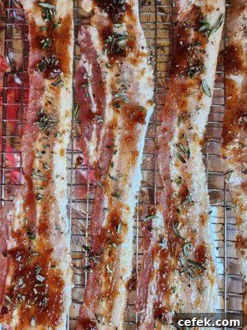 Raw bacon on a baking sheet with fig jam and rosemary on top.