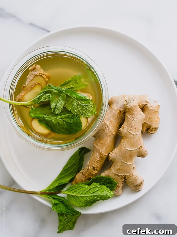 The top of a ginger-mint cooler alongside fresh ginger on a white plate.
