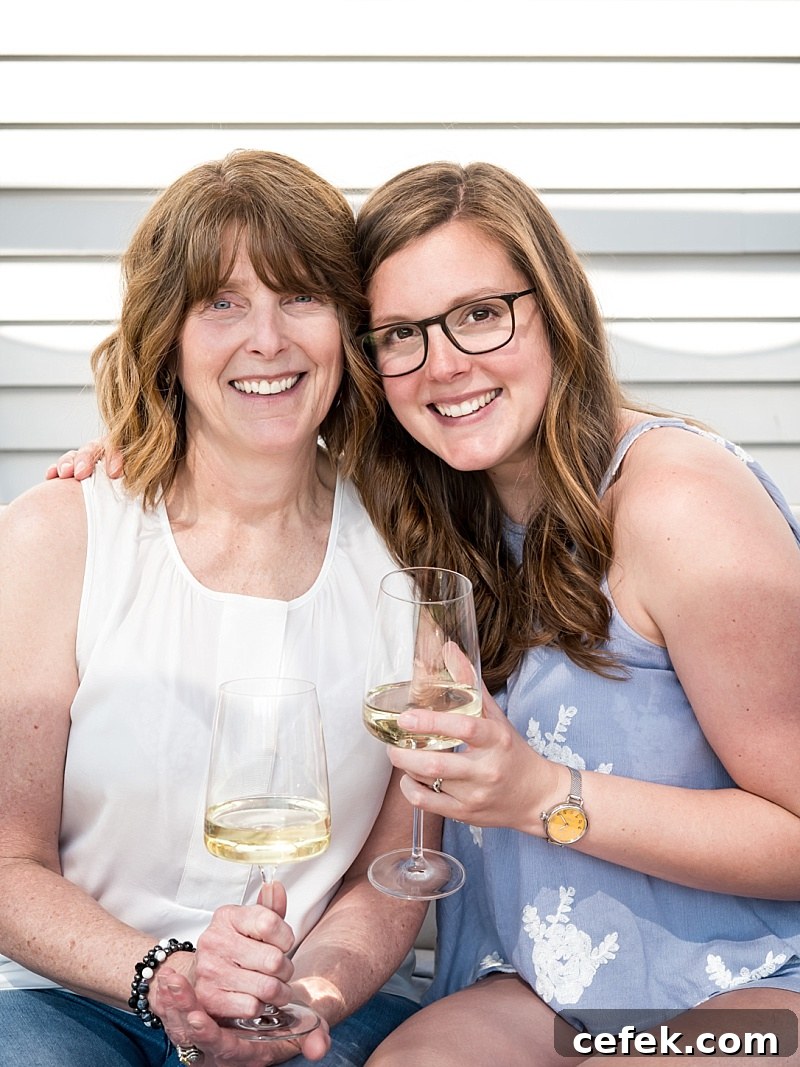 lexi and beth of crowded kitchen pose together with wine glasses