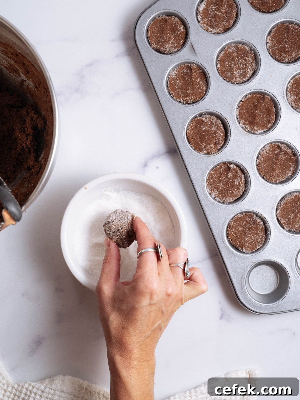 Rolling chocolate cookies in sugar before baking