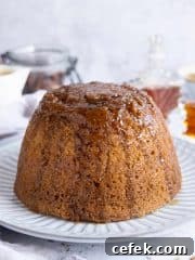 Close up of vegan steamed maple syrup pudding on a white plate.