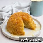 Vegan steamed syrup sponge pudding on a plate with a jug of custard.