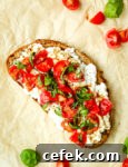 A slice of toast with cottage cheese, quartered grape tomatoes,and strips of basil