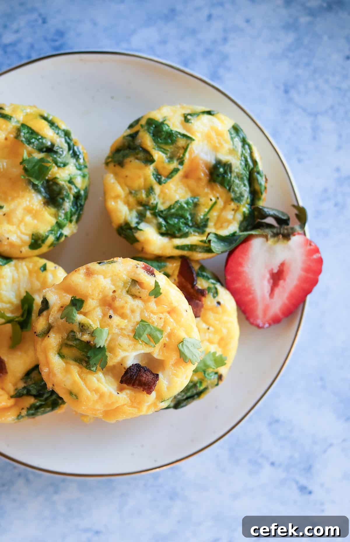 A plate of egg bites with a sliced strawberry.