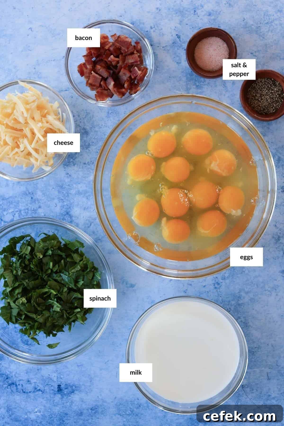 The ingredients for a recipe for fried eggs with spinach and cheese on a blue background.