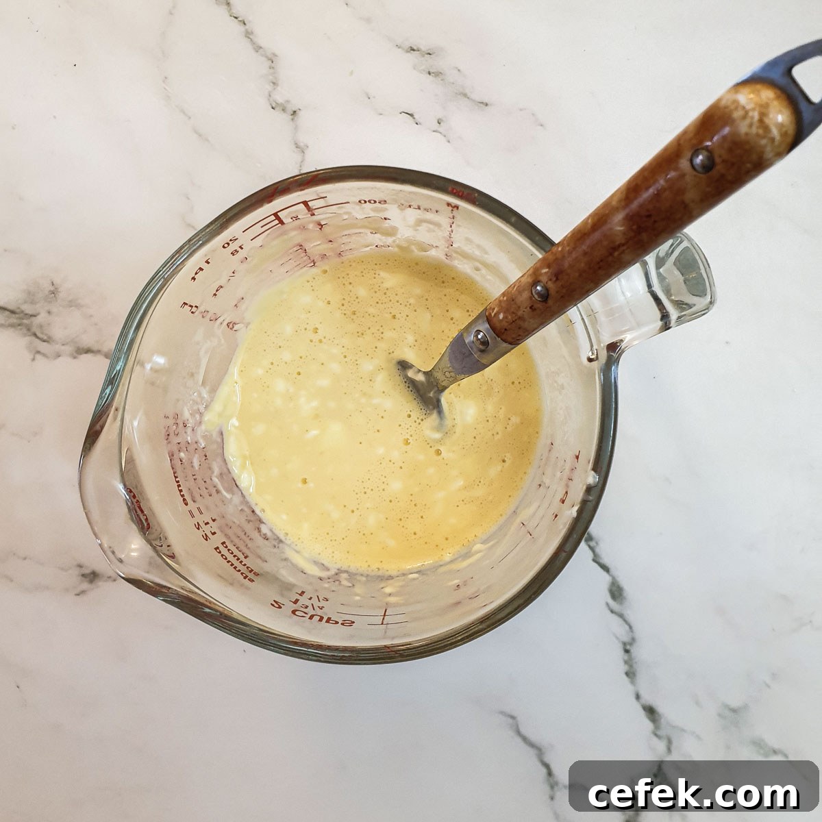 Egg and cream cheese being mixed in a jug.