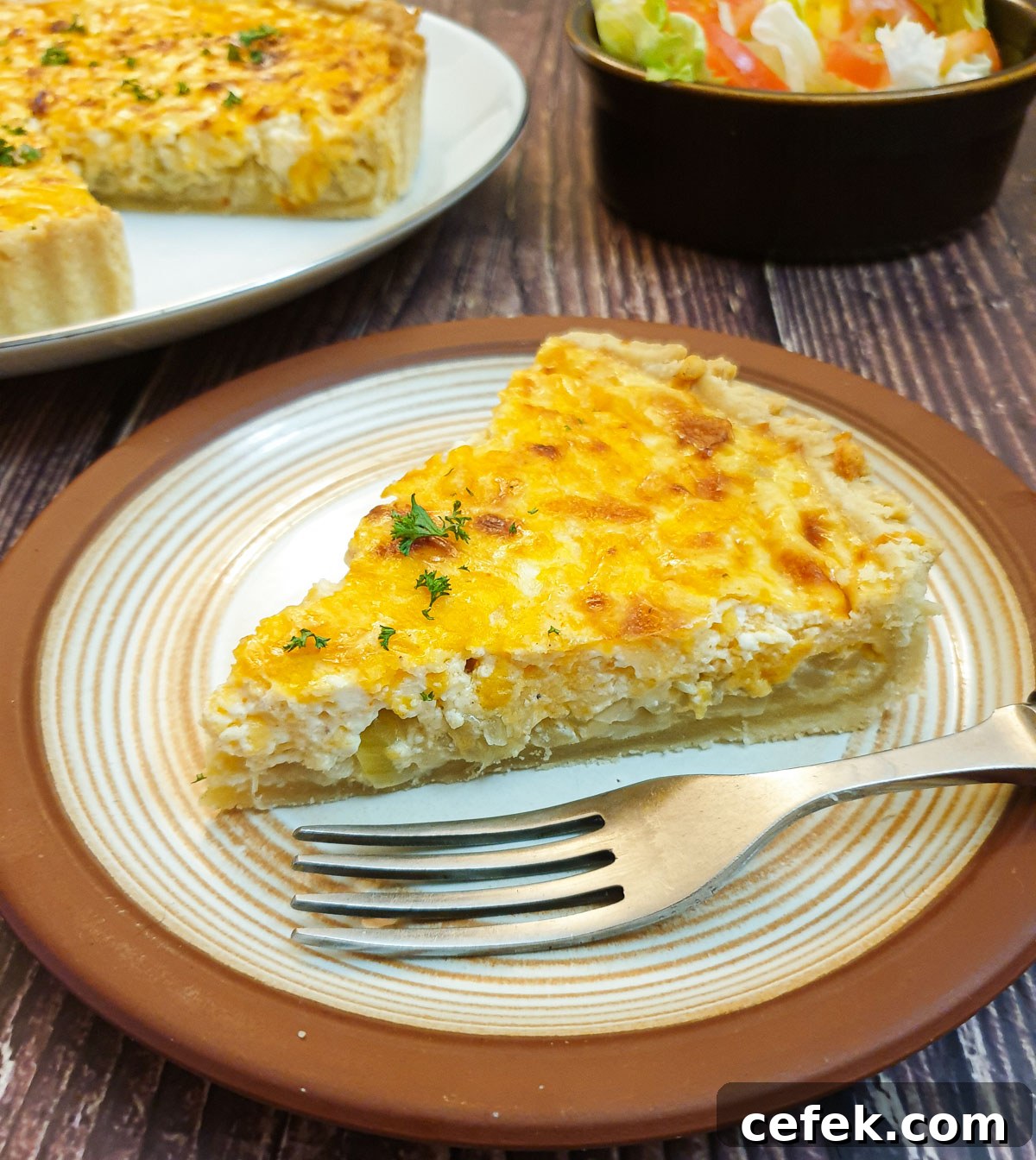 A slice of cheese and onion quiche on a plate.