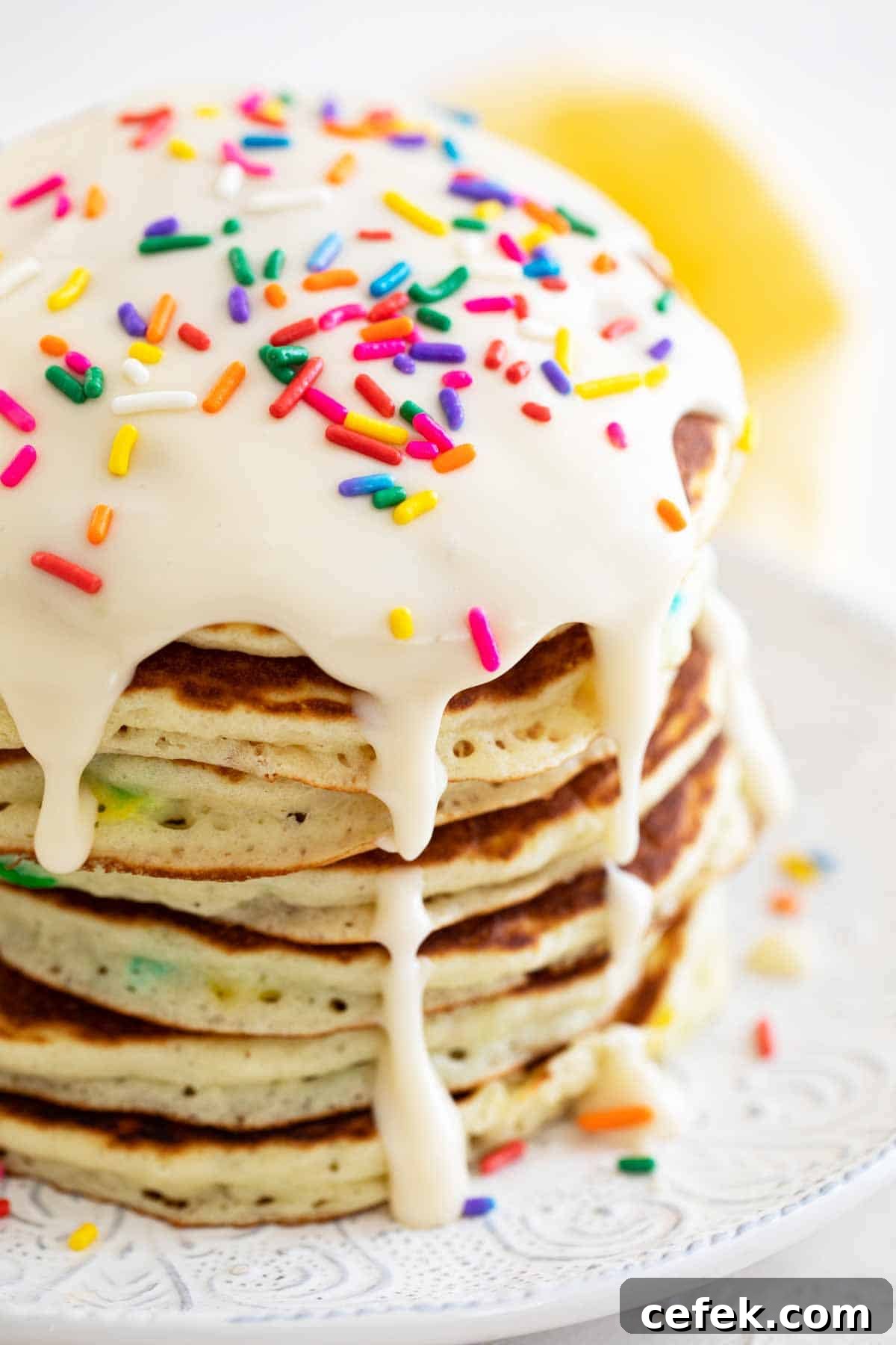 large stack of funfetti pancakes topped with icing and sprinkles