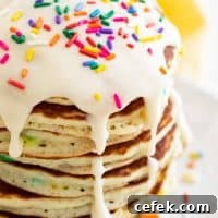 large stack of funfetti pancakes topped with icing and sprinkles