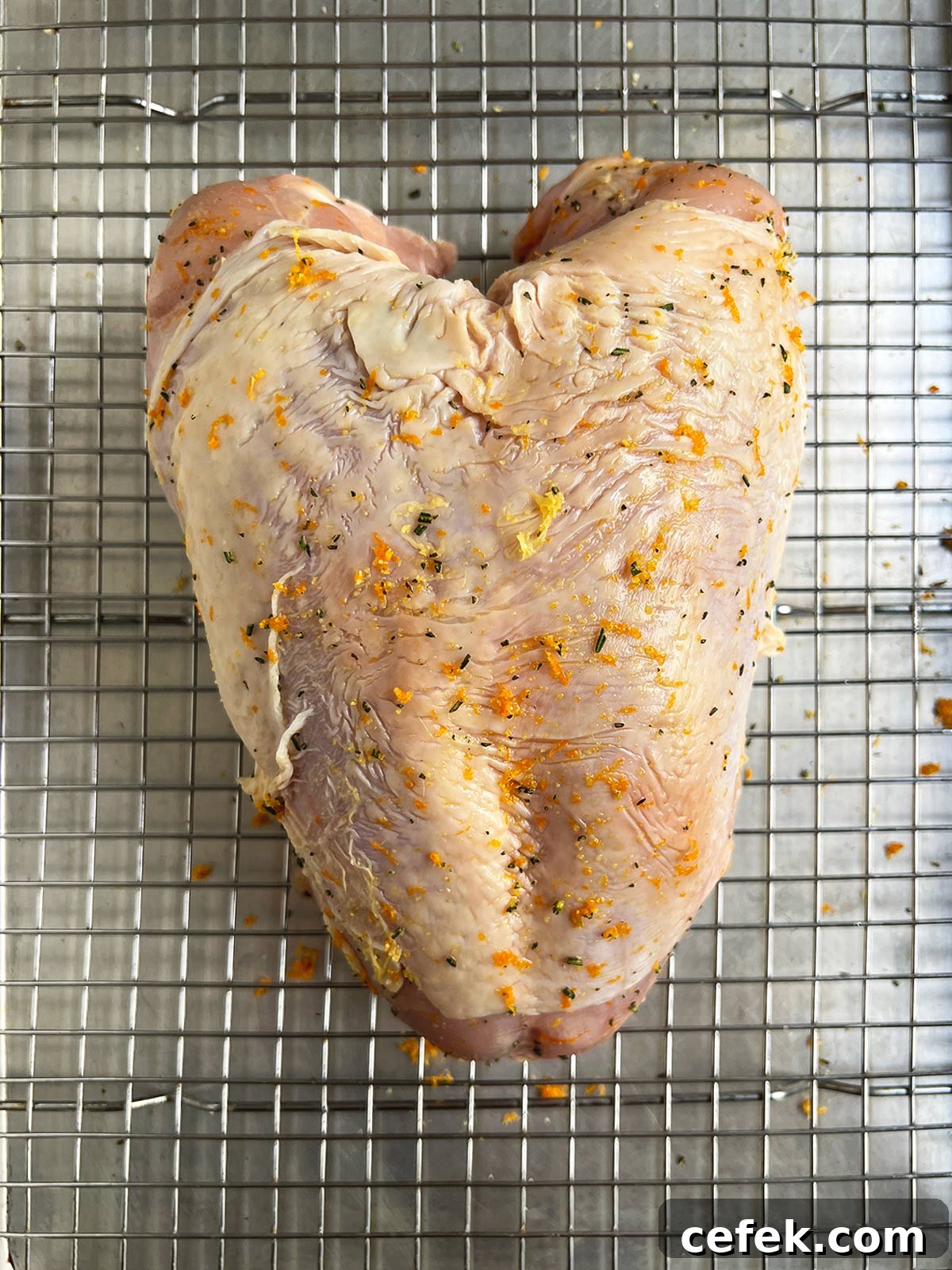 Dry brine rubbed onto the turkey breast which is laying on a rack on a sheet tray.