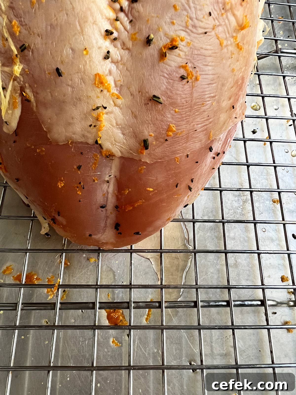 Close up of brined turkey showing that some liquid has release on the bottom of the pan.