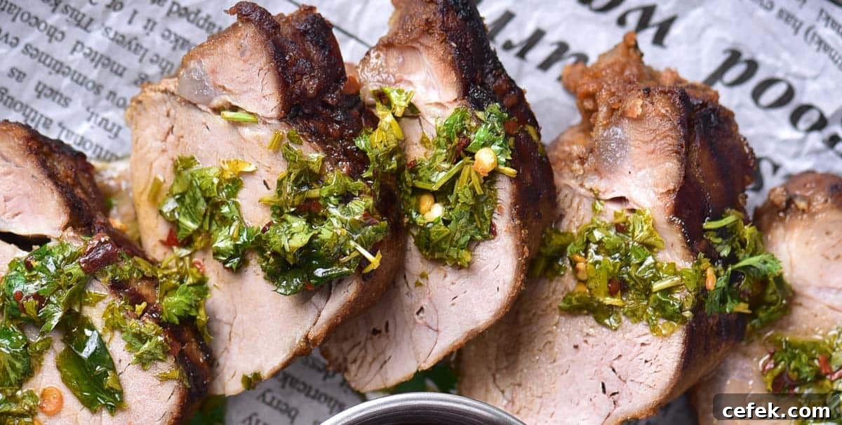 Close-up of grilled pork tenderloin slices with a thick coating of chimichurri sauce.