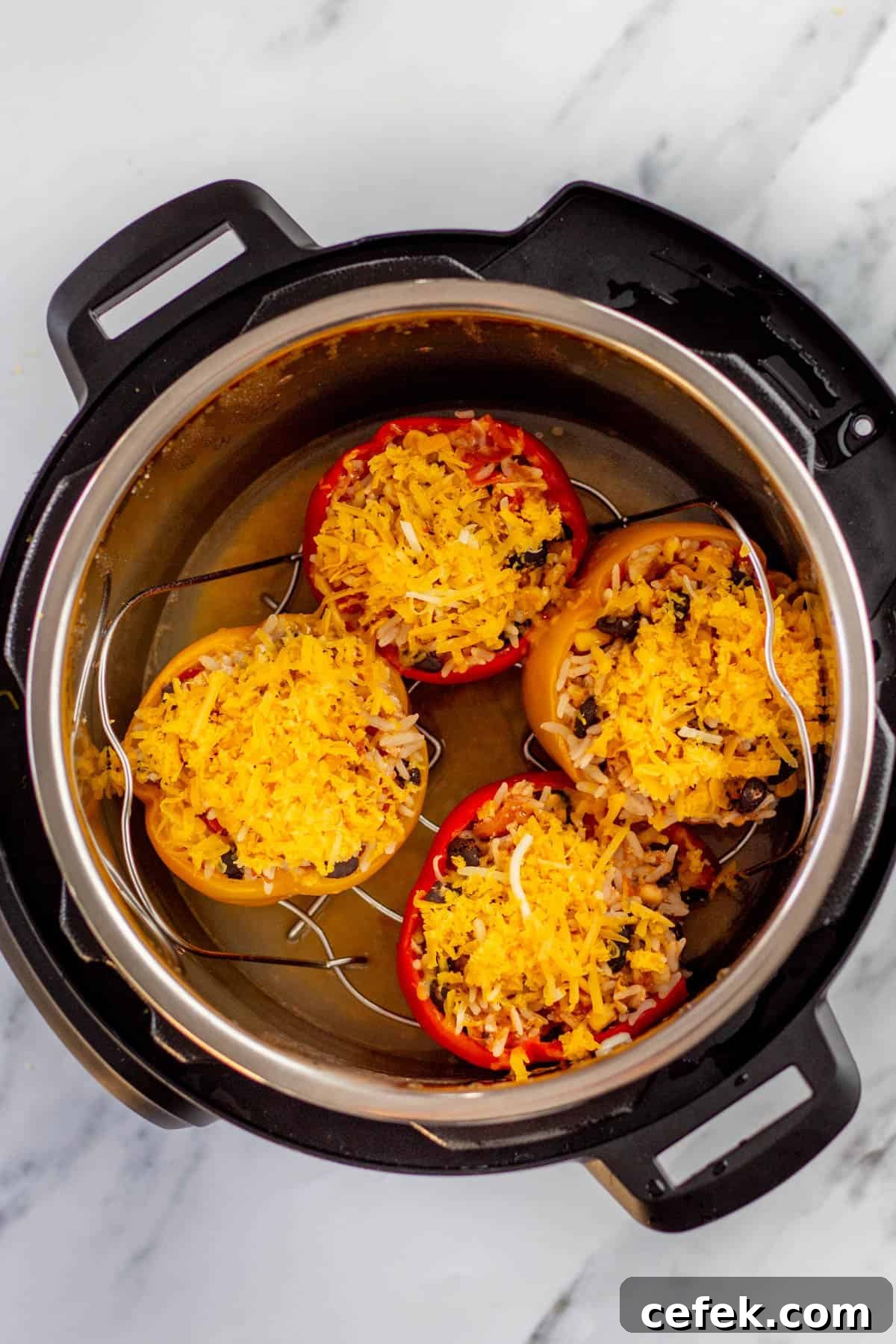 Three stuffed peppers topped with shredded cheese in an instant pot.
