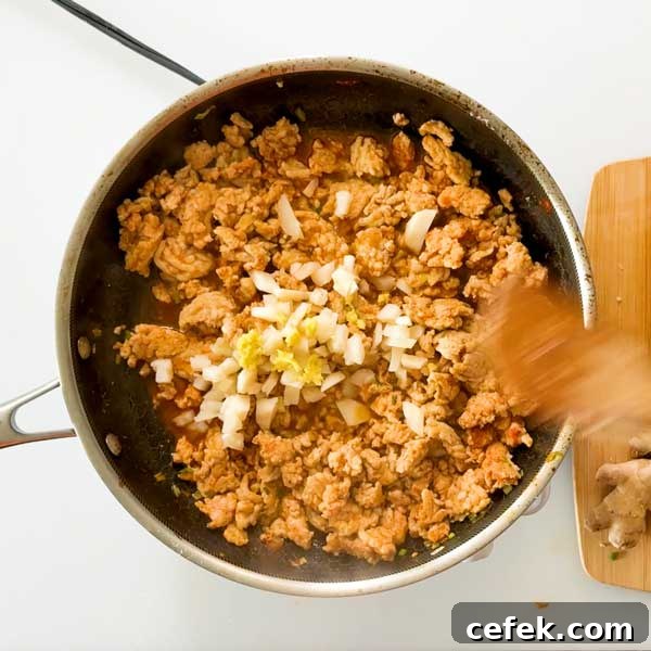Adding the water chestnuts and ginger to the cooked meat.