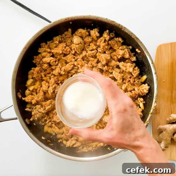 Adding the cornstarch slurry to the cooked meat.