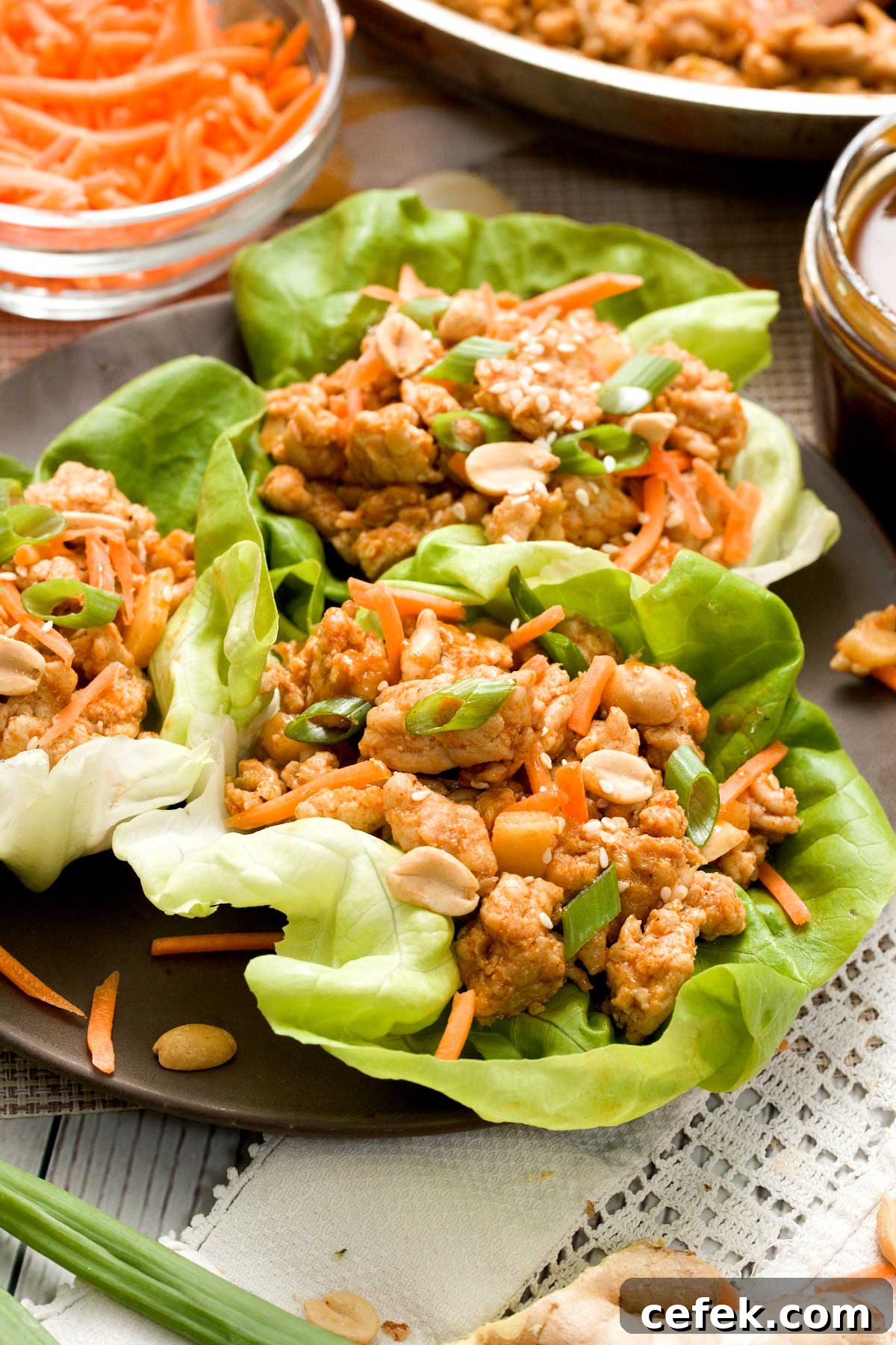 Asian ground chicken filling in lettuce wraps with sliced carrots.