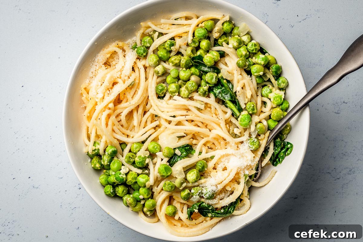 Pasta with peas parmesan and spinach in a bowl.