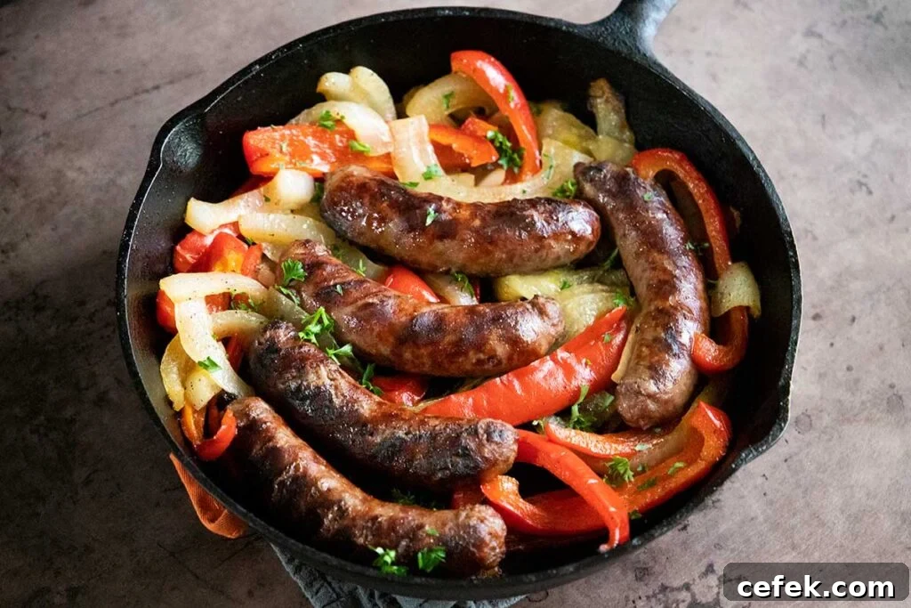 beer brats with peppers and onions, cooked, in a cast iron skillet