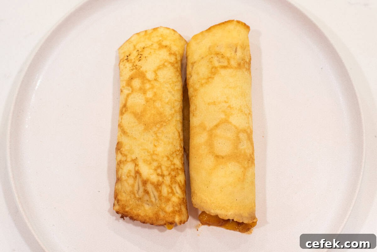 2 rolled up mango crepes on plate.