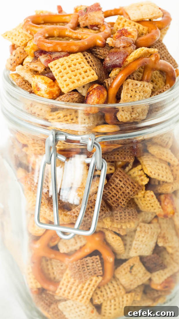 A glass jar with a hinged lid is overflowing with duck fat Chex mix.