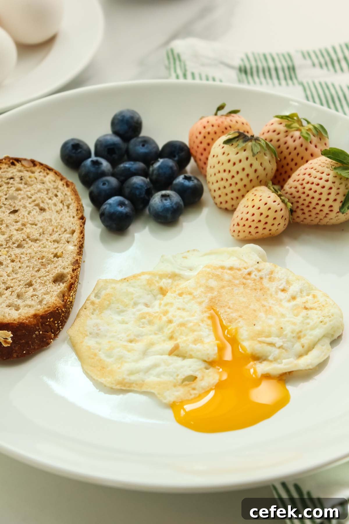 over easy egg with yolk coming out of egg, toast, and berries.