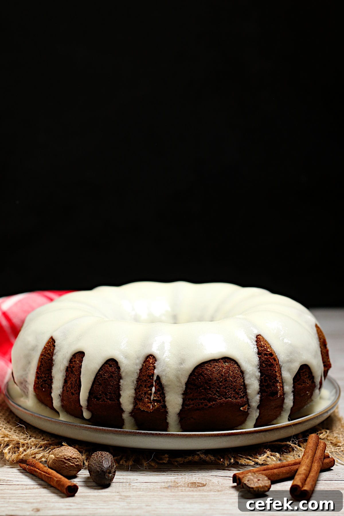 A whole Pumpkin Spice Bundt Cake with glaze on a large white plate.