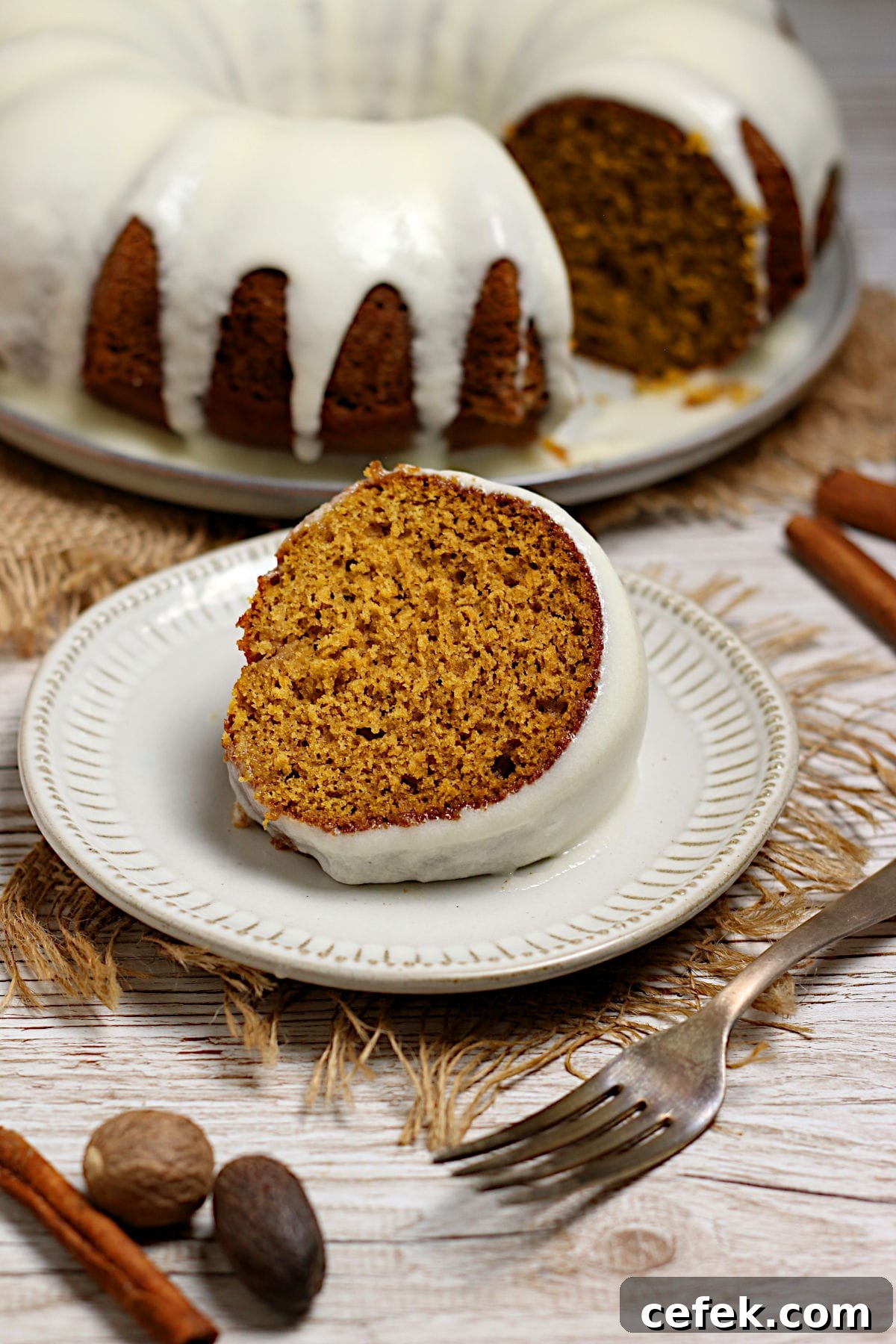 A slice of Pumpkin Spice Bundt Cake with glaze on a white plate.