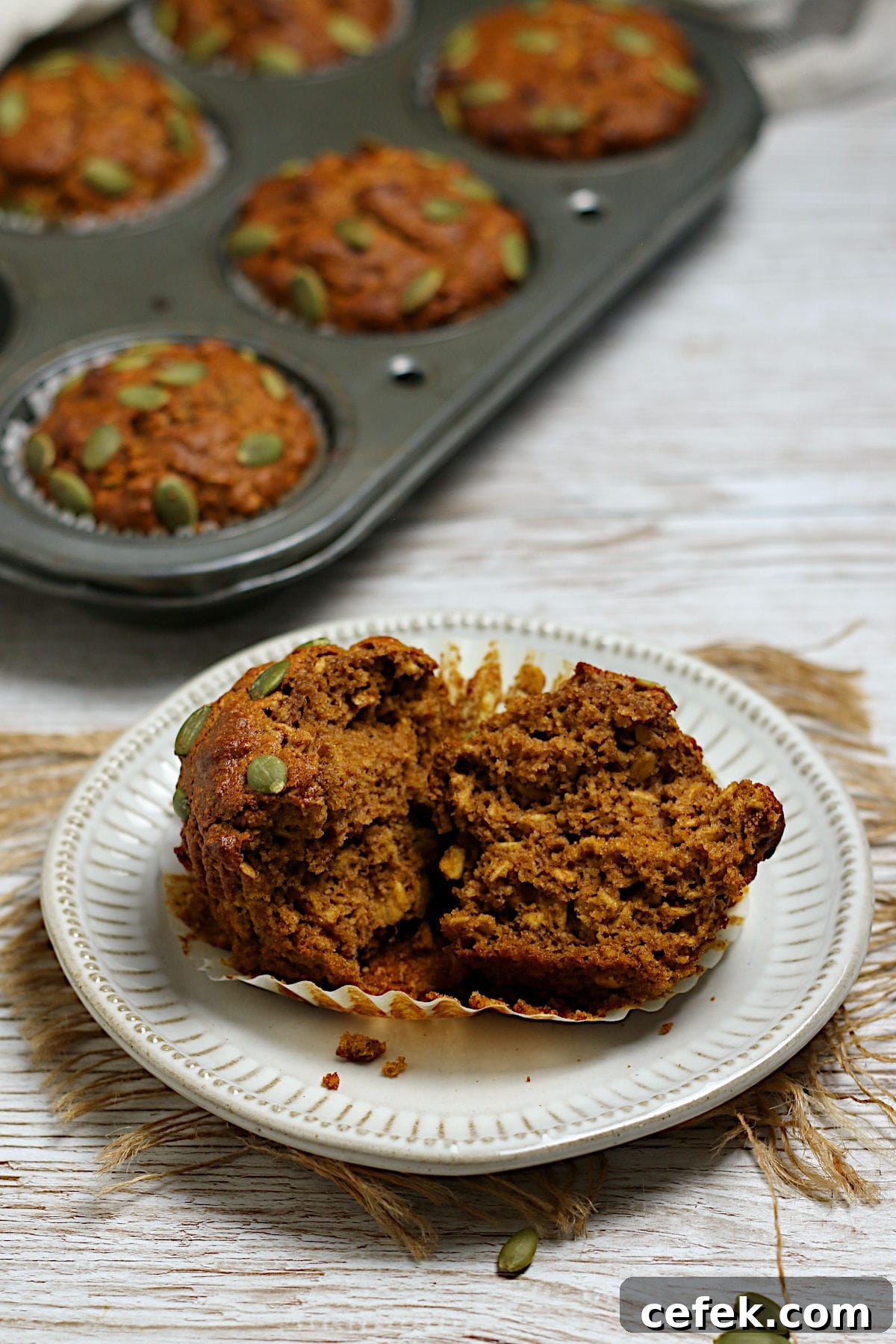 An Oatmeal Pumpkin Spice Muffin split in half on a plate.