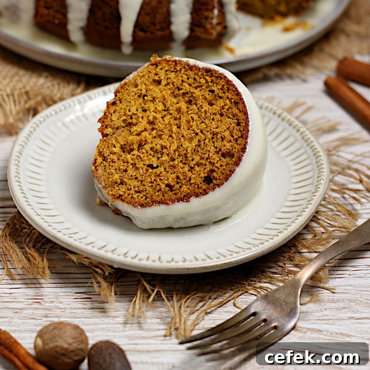 A slice of Pumpkin Spice Bundt Cake with glaze on a white plate.