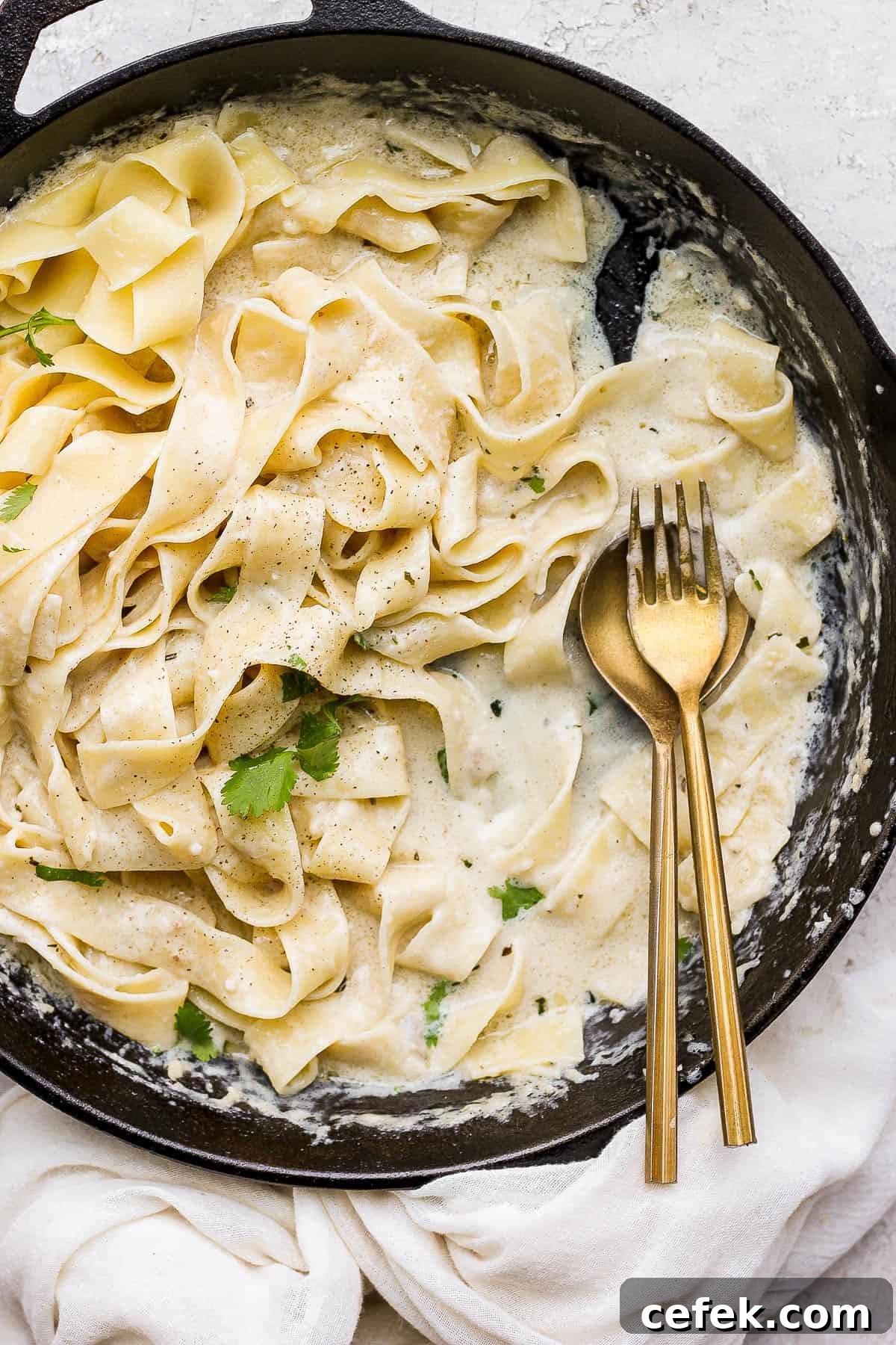 The noodles and alfredo sauce mixed completely in the pan with a spoon and fork.