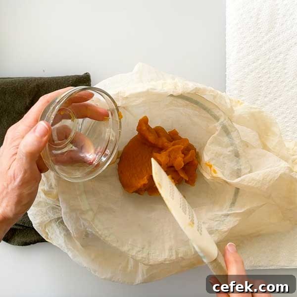 Scraping the pumpkin paste into a small bowl.