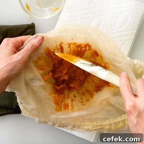 Scraping the pumpkin paste out of the strainer bag.