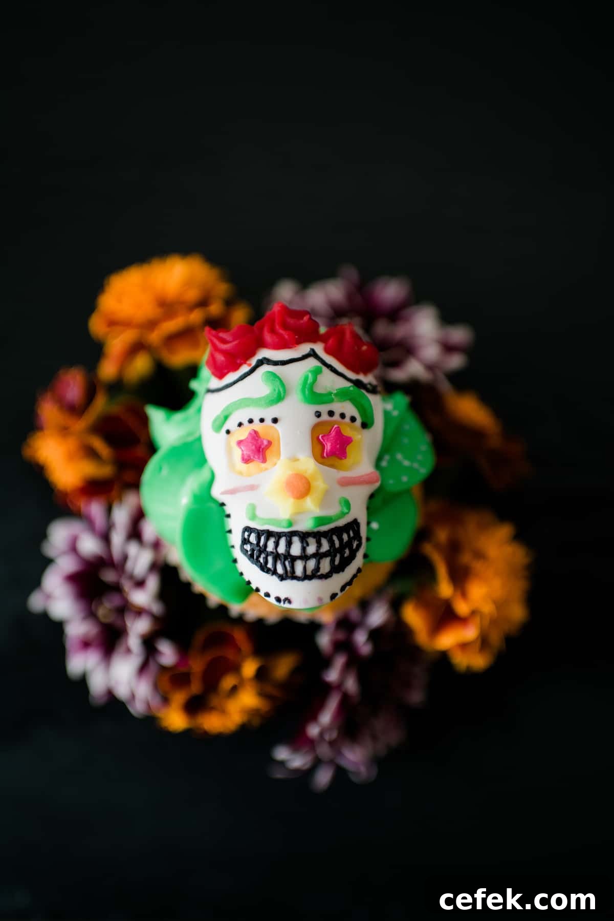 Overhead view of festive DIY Dia de los Muertos candy skulls decorated with colorful frosting and served on top of a cupcake