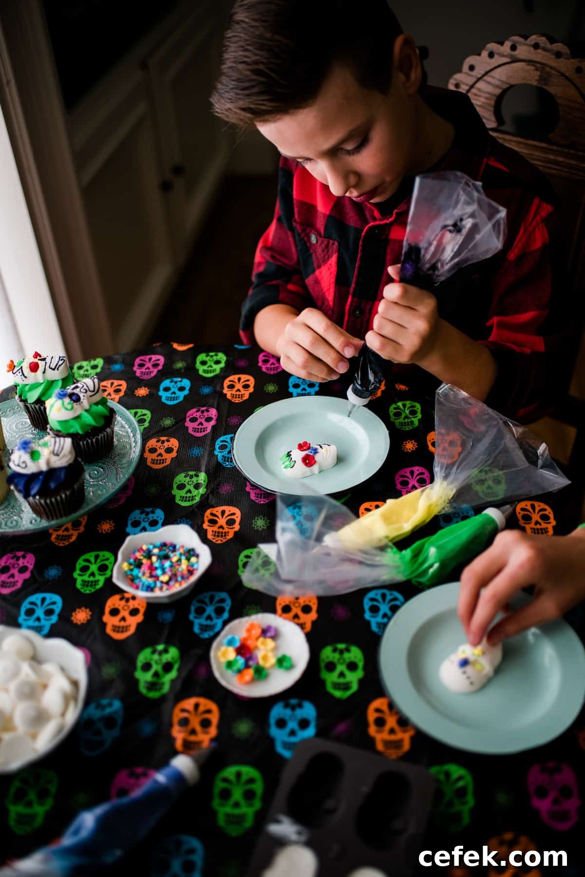 Children decorating Dia de los Muertos candy skulls with colorful frosting, candy flowers, and sprinkles on a skull tablecloth
