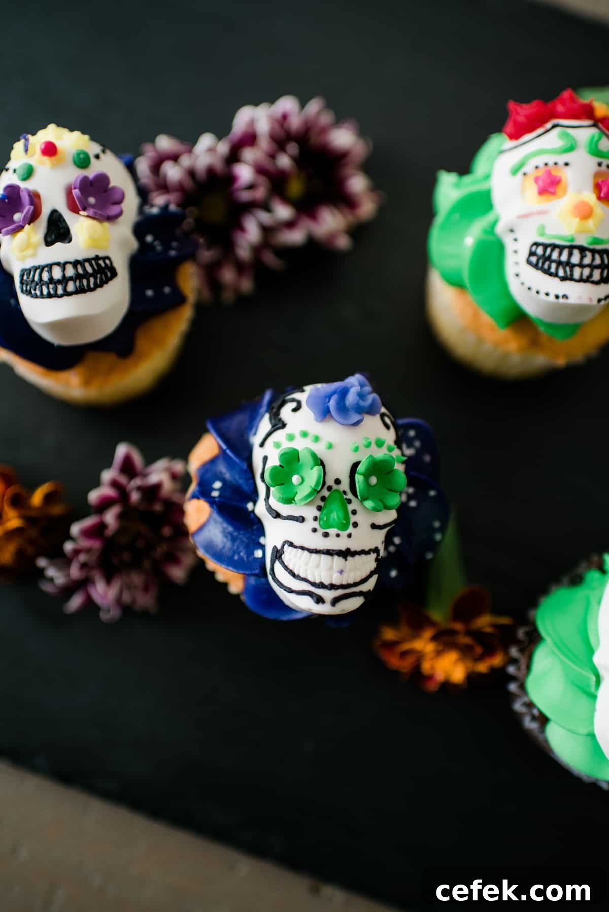 Overhead view of festive DIY Dia de los Muertos candy skulls decorated with colorful frosting and served on top of a cupcake