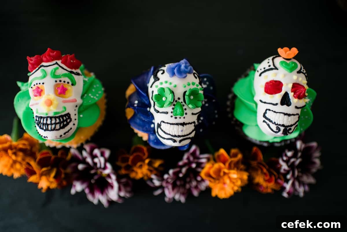 Overhead view of festive DIY Dia de los Muertos candy skulls decorated with colorful frosting and served on top of a cupcake