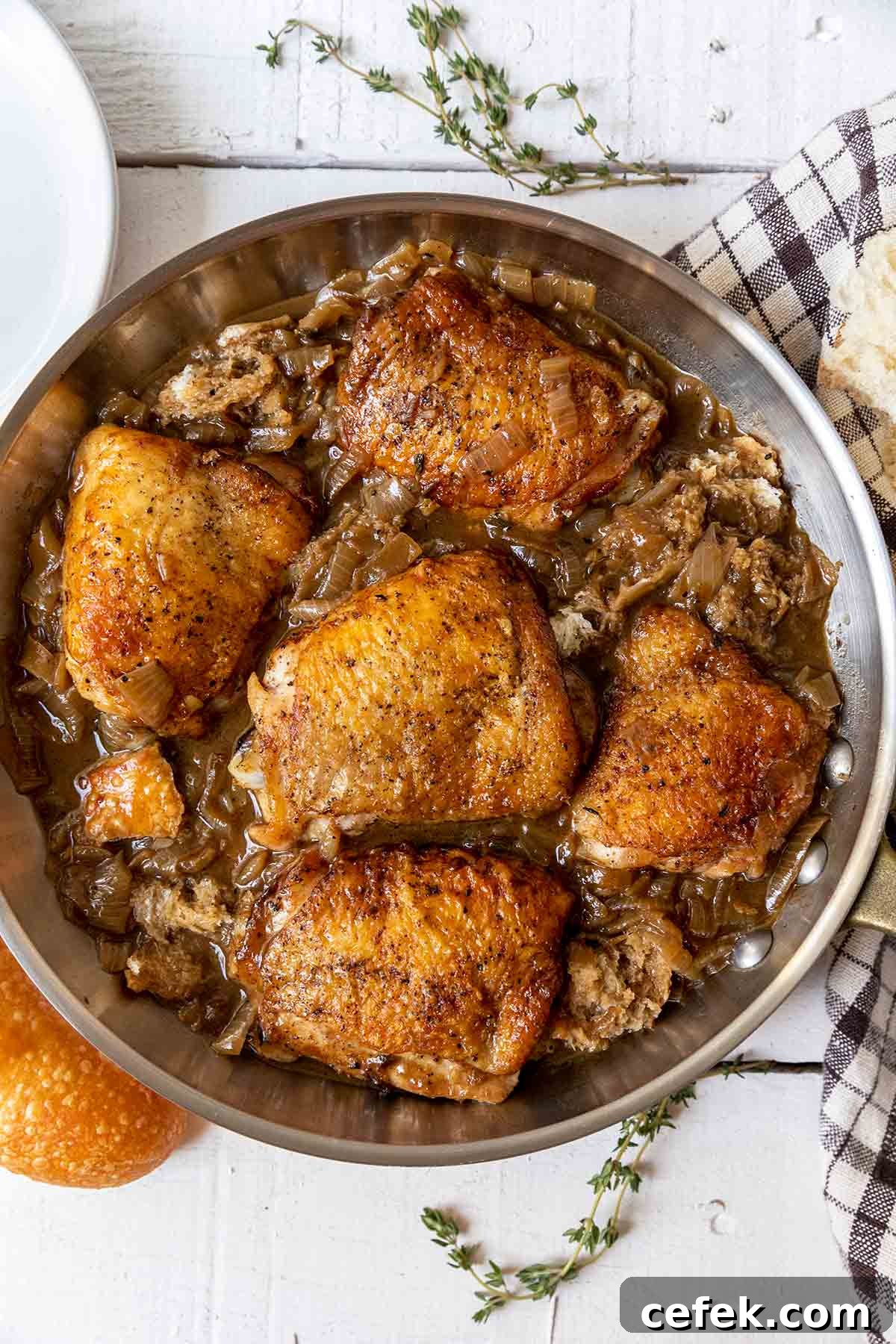 French onion skillet chicken with caramelized onions and chunks of bread tucked around the thighs