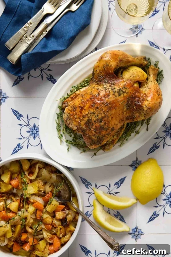 A whole roast chicken on a platter with a bowl of roasted root vegetables nearby.