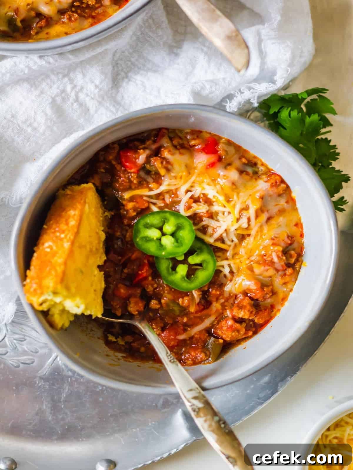 A bowl of chili with a piece of cornbread.