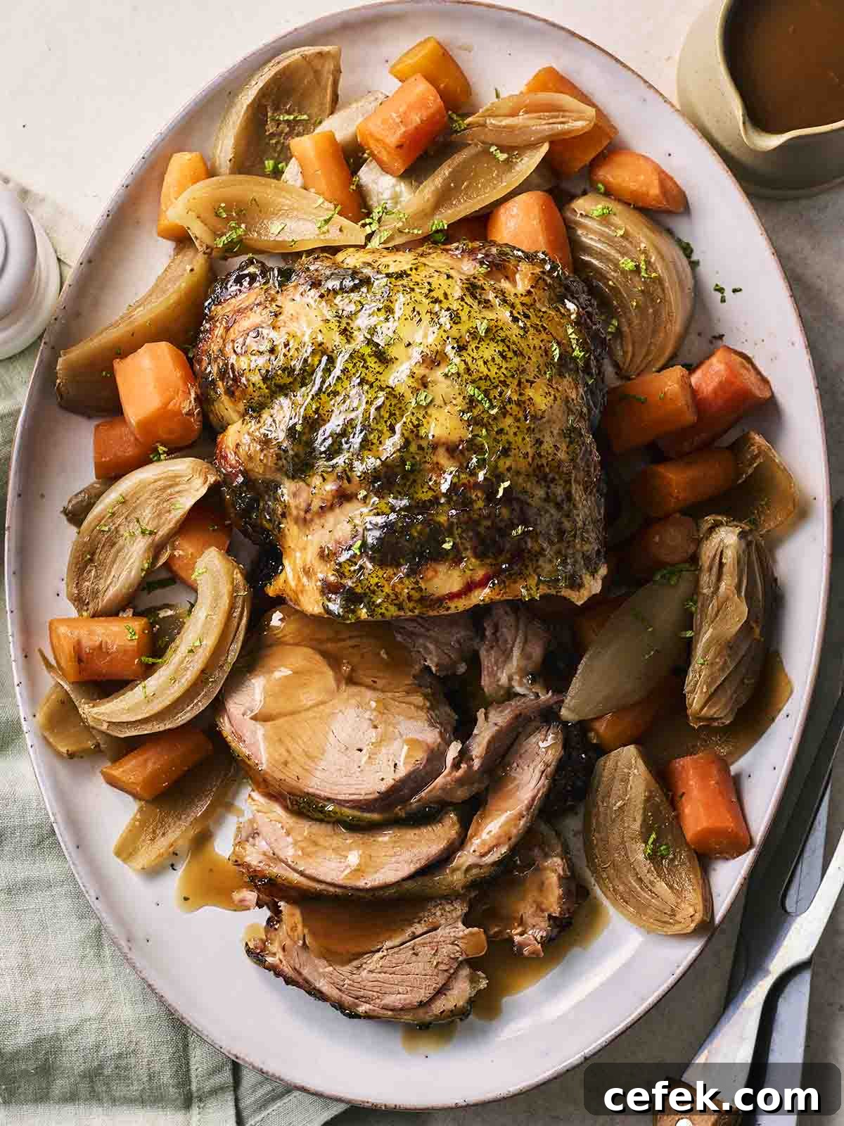 A serving plate with a leg of lamb in the middle, surrounded by cooked vegetables, straight out of the slow cooker.